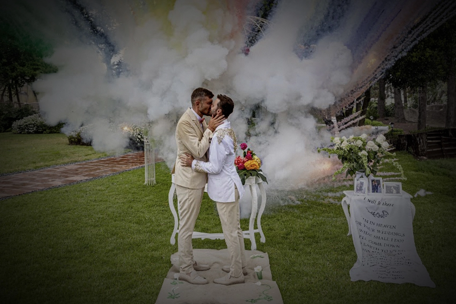 Dos novios celebrando su boda con humo de colores en el jardín
