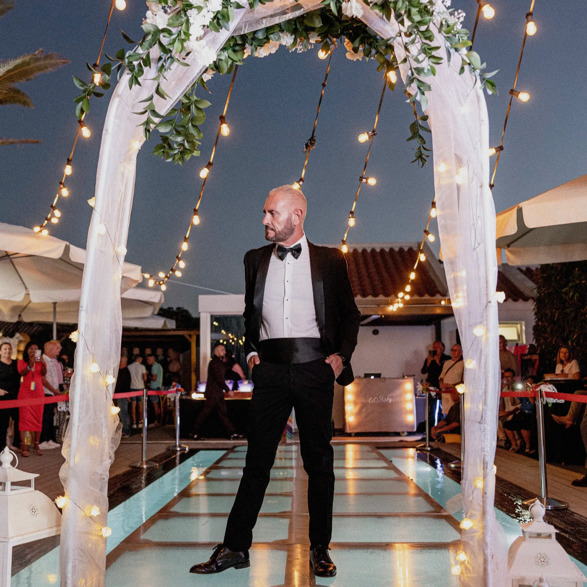 Novio bajo el arco floral iluminado