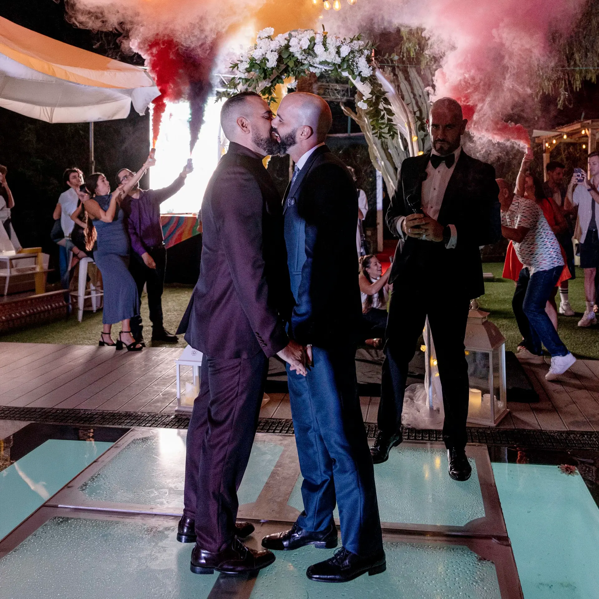 Dos novios besándose entre humo de color